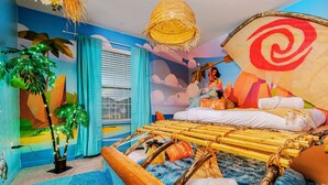 Une pièce avec un lit, une suspension décorative, une plante et une fenêtre avec des rideaux.