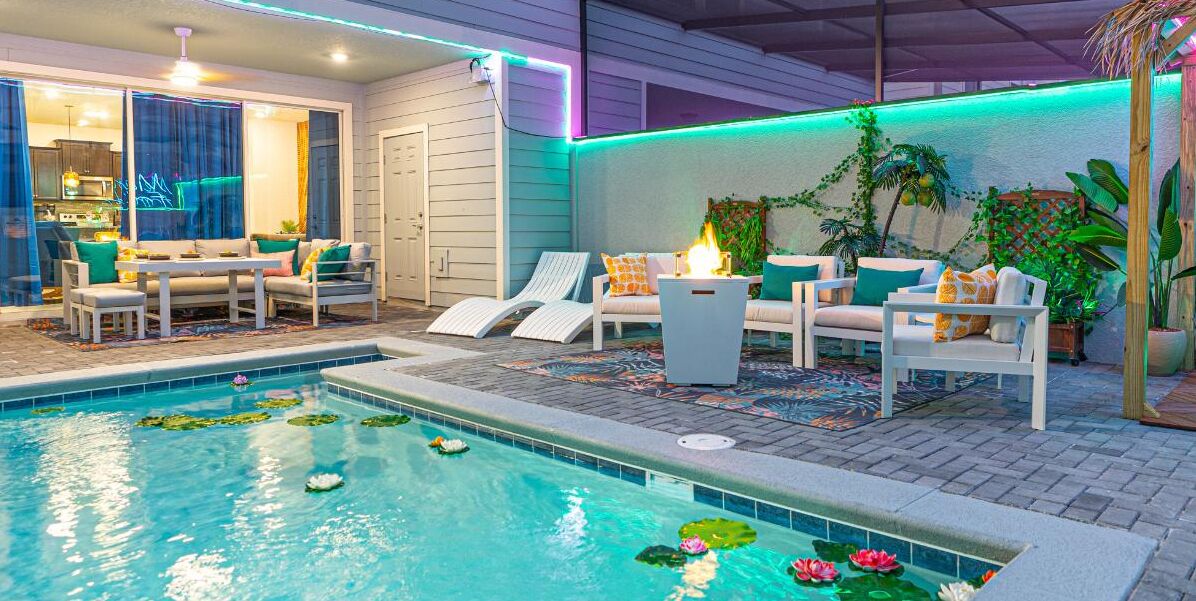 An outdoor pool area with lounge chairs, a fire pit, and a dining set.
