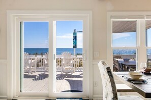 A room with a view of a beach deck, a sign reading "BEACH", and a dining area with a table and chairs. - Gorgeous Oceanfront Home - Huge Deck To Enjoy the Ocean Breezes (Oak Island)
