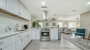 A modern kitchen with white cabinets, stainless steel appliances, and a central island.