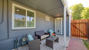 A covered patio with wicker furniture, a small table, and a decorative vase.