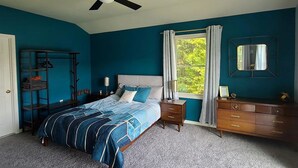 A bedroom with a bed, a dresser, a nightstand, a ceiling fan, a window with curtains, and a mirror. - Private Riverfront Home with dock (Hague)