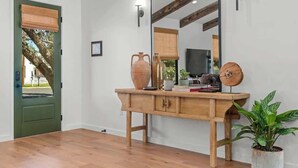 A wooden console table with a mirror, a potted plant, and decorative items. - 6 Mins from Main St, Hot tub, Chef's Kitchen! (Fredericksburg)