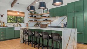 A kitchen with green cabinets, a marble island, and bar stools. - 6 Mins from Main St, Hot tub, Chef's Kitchen! (Fredericksburg)