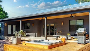 A modern house with a covered patio, a hot tub, and a grill area. - 6 Mins from Main St, Hot tub, Chef's Kitchen! (Fredericksburg)