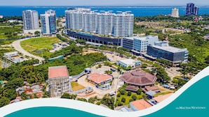 A coastal cityscape with modern high-rise buildings, a marina, and a mix of residential and commercial structures. - Mactan Newtown C by HiveRooms (Lapu-Lapu)