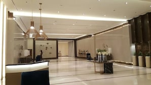 A spacious lobby with a reception desk, modern pendant lighting, and a marble floor. - Mactan Newtown C by HiveRooms (Lapu-Lapu)