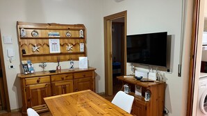 A cozy kitchen with wooden cabinets, a dining table, and a TV. - Valentina's Rent Apartment (Fertilia)