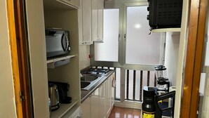A compact kitchen with a Bosch washing machine, a coffee maker, a stove, and a window with a view. - Valentina's Rent Apartment (Fertilia)