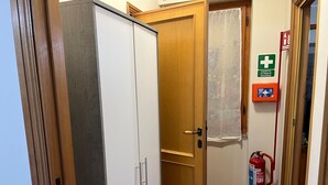 A hallway with a wooden door, a fire extinguisher, and a first aid kit on the wall. - Valentina's Rent Apartment (Fertilia)