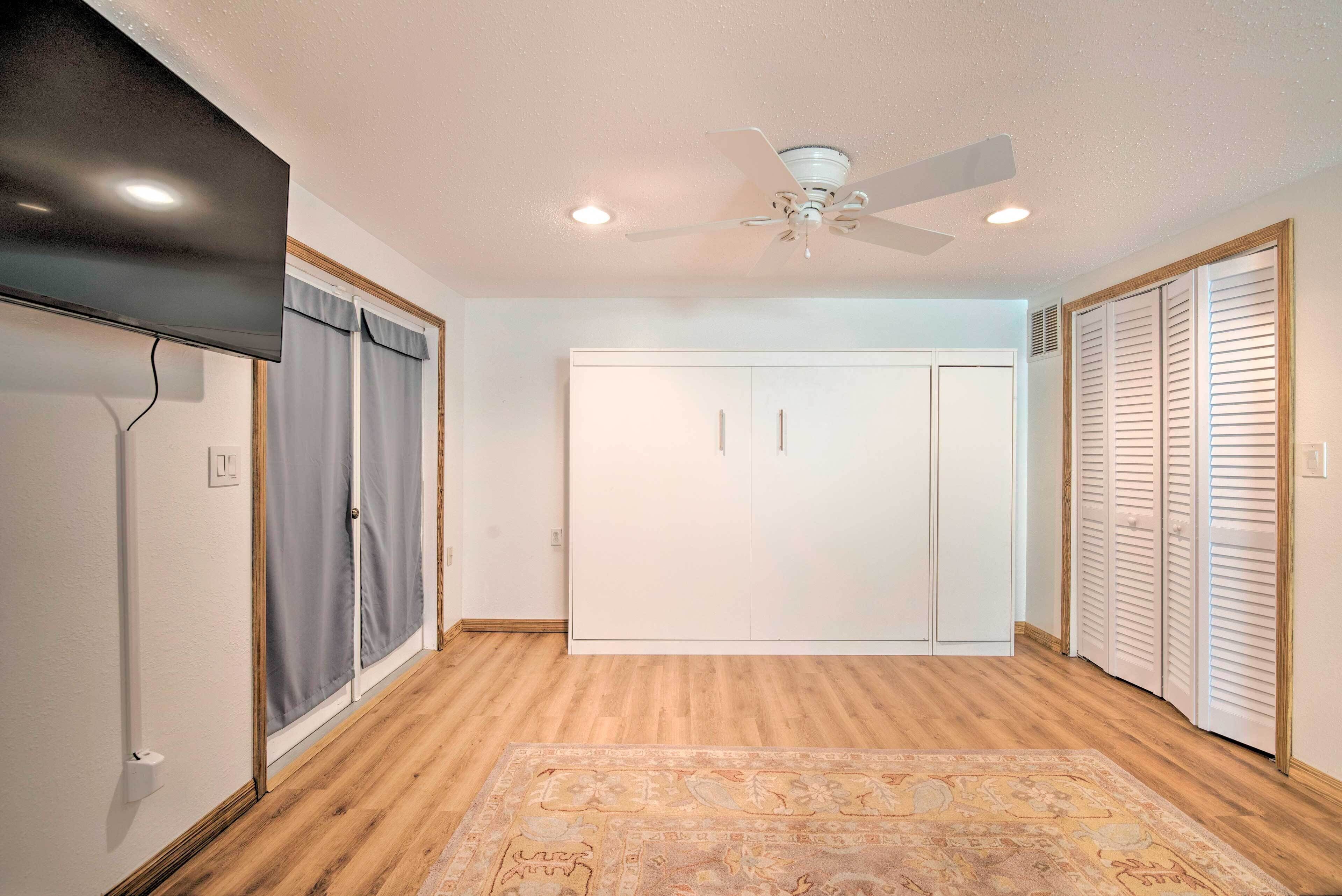 Una habitación con ventilador de techo, televisión, armario y alfombra estampada.