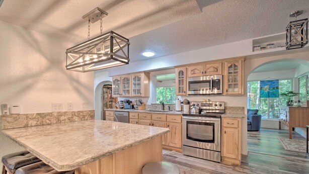 A spacious kitchen with a large island, wooden cabinets, stainless steel appliances, and a hanging light fixture. - Withlacoochee River Chalet Great River View, near Rainbow River (Dunnellon)