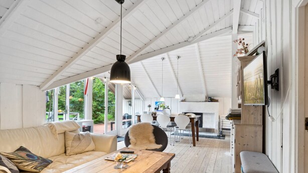 A spacious living area with a wooden coffee table, a sofa, and a dining table. There is a fireplace and a television mounted on the wall.