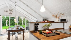 A modern kitchen with a wooden countertop, a dining area with a table and chairs, and a view of the garden through large windows.