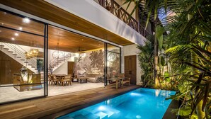 Ein modernes Haus mit Schwimmbad, Holzterrasse und tropischen Pflanzen.