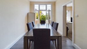 A conference room with a long table and chairs, a whiteboard, and a view of a garden through large windows.