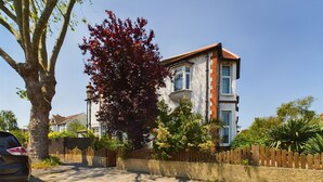 A residential building with a brick facade, multiple windows, and a surrounding fence.