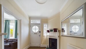 A hallway with a white door, a fireplace, and a large mirror on the wall.