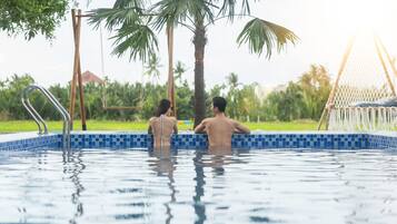 Una piscina al aire libre, sombrillas, sillones reclinables de piscina