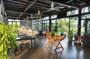 Un espacio interior amplio con suelo de madera, ventanas grandes y ventiladores de techo.