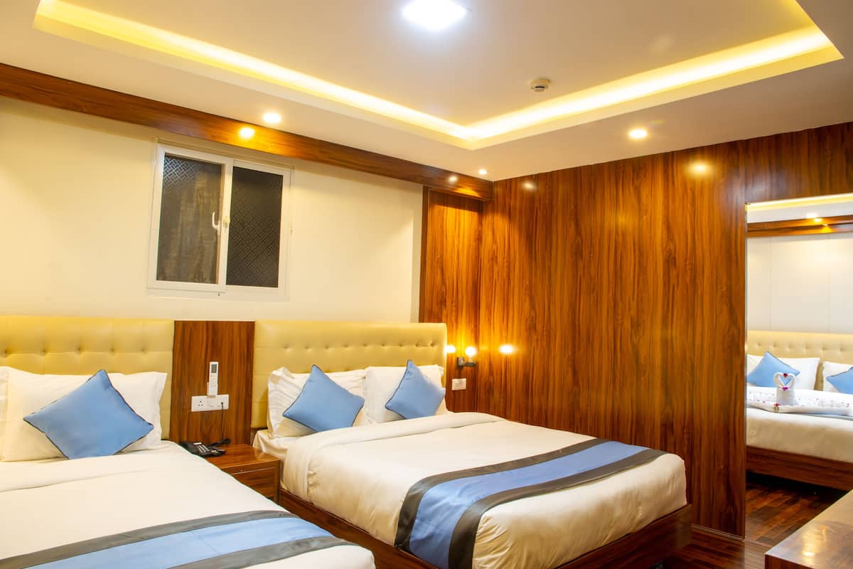 A hotel room with two beds, wooden paneling, and a modern ceiling design.