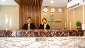 A reception desk with a marble top and a "RECEPTION" sign. There are clocks displaying times from the U.S.A, Nepal, and London. A logo for "Dreams Connect" is visible on the wall. - HOTEL DREAMS CONNECT (Kathmandu)