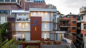 A hotel with a modern design, featuring a prominent logo, outdoor seating area, and a staircase leading to an upper level. - HOTEL DREAMS CONNECT (Kathmandu)