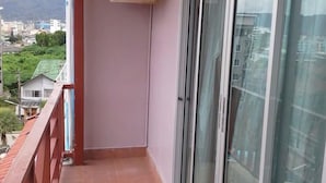 A balcony with a red railing, a sliding glass door, and an air conditioning unit mounted on the wall. - Vech guesthouse2 (Patong)