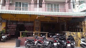 A building with a restaurant named 'Green Ice' on the ground floor. There are several motorcycles parked in front. - Vech guesthouse2 (Patong)