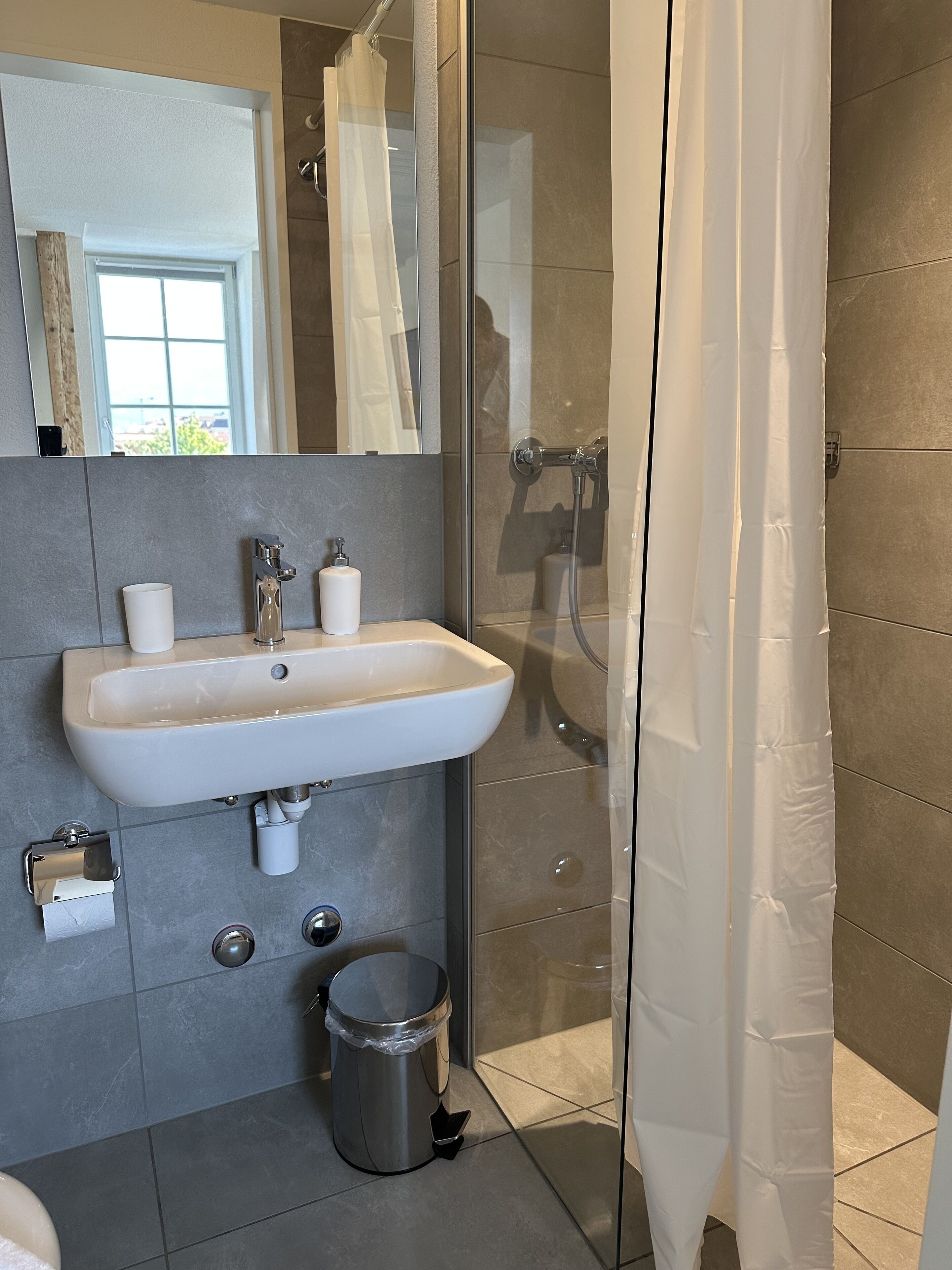 Une salle de bain moderne avec une douche à parois de verre, un lavabo blanc et des toilettes.