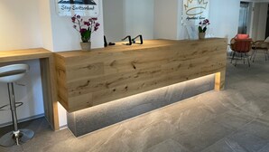 Una reception con finiture in legno, un'orchidea in vaso e due cartelli: "Stay Switzerland" e "Aparthotel King".