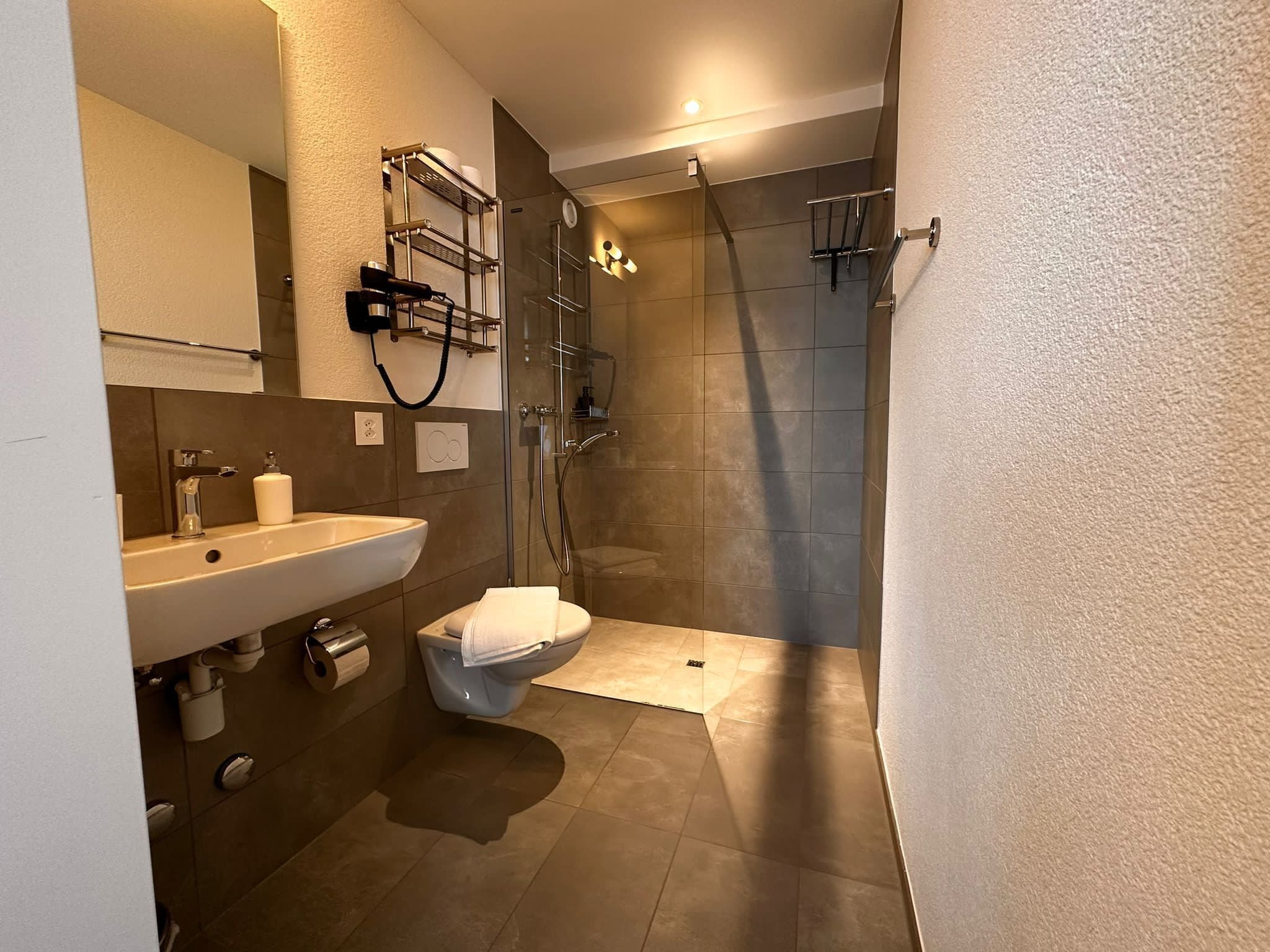 A modern bathroom with a sink, toilet, and glass-enclosed shower.