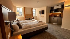 Una camera d'albergo moderna con un letto grande, una televisione, una scrivania e angolo cottura.