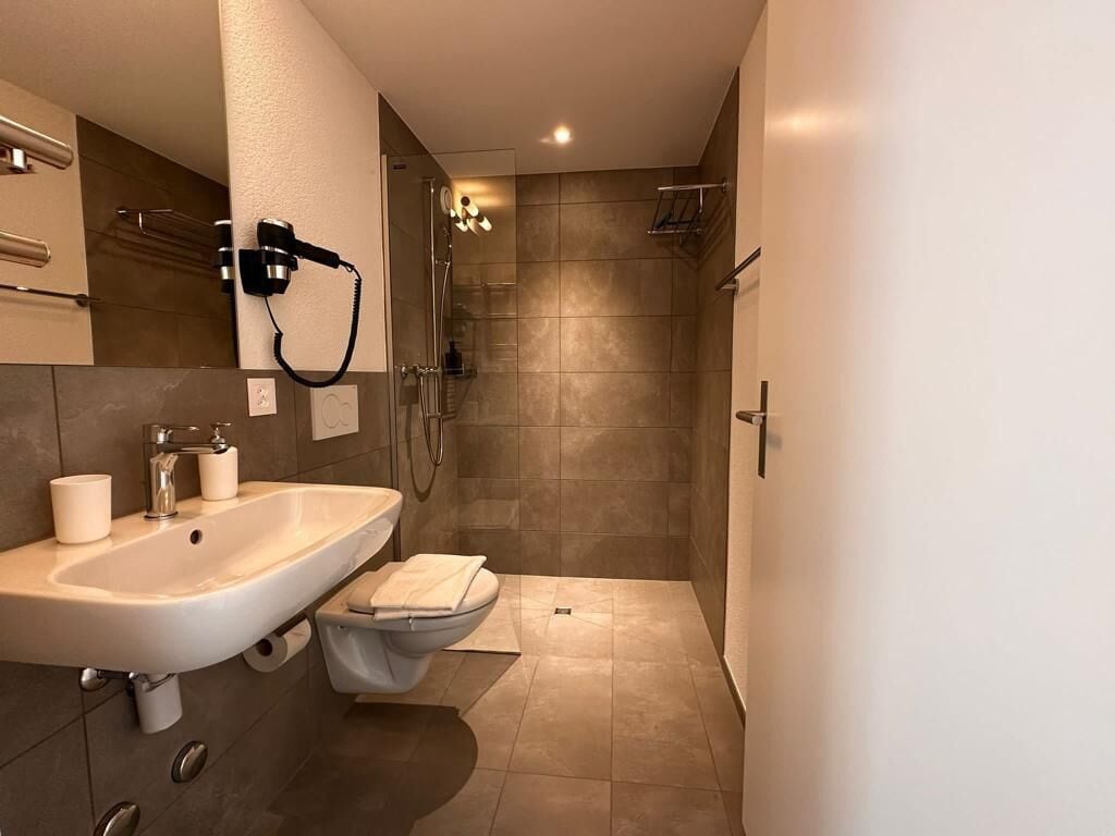 Un baño moderno con lavamanos, inodoro y zona de ducha.