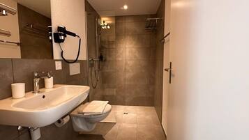 Un baño moderno con lavamanos, inodoro y zona de ducha.