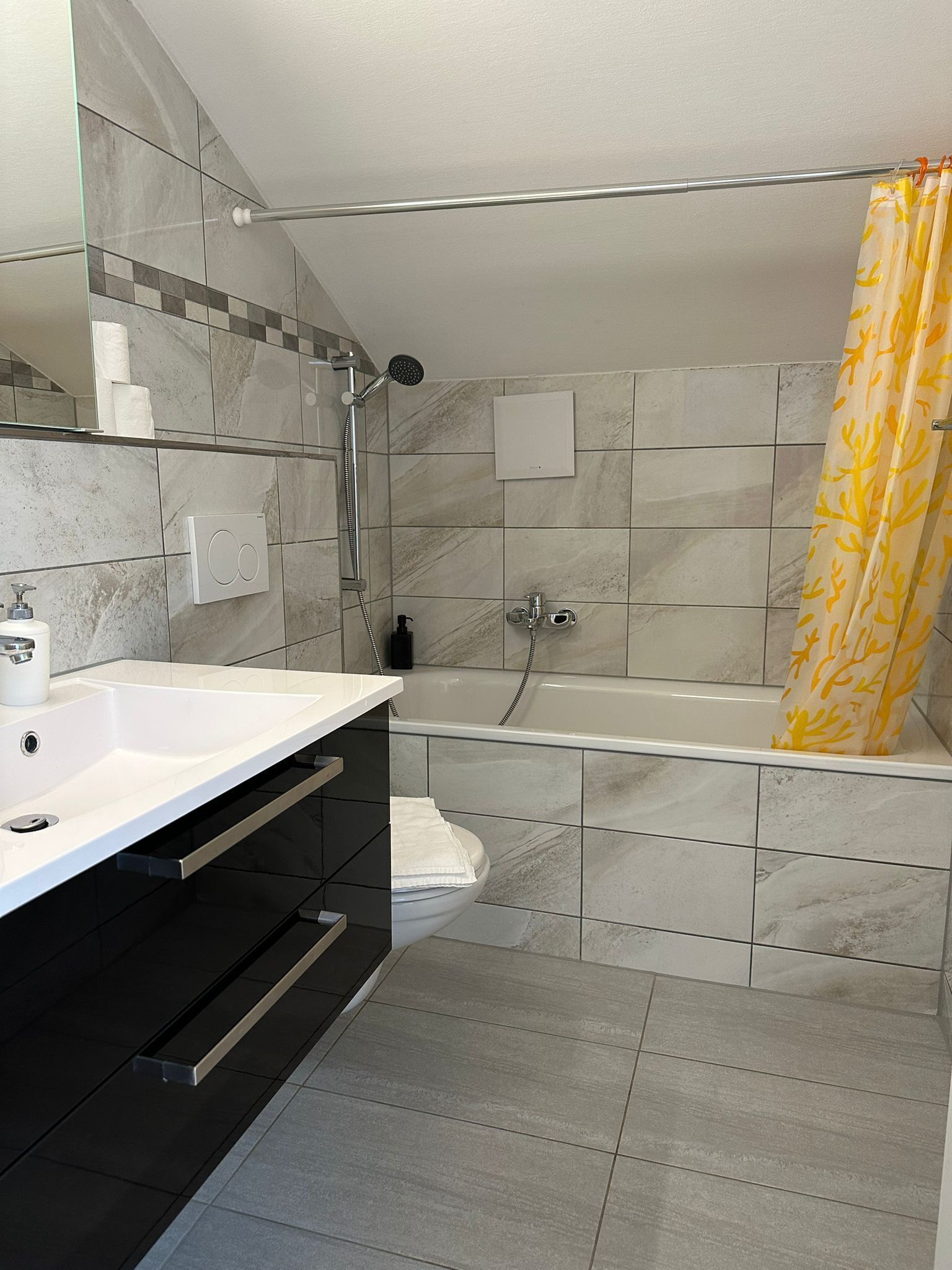Un bany modern amb un lavabo blanc, un armari negre i una banyera.