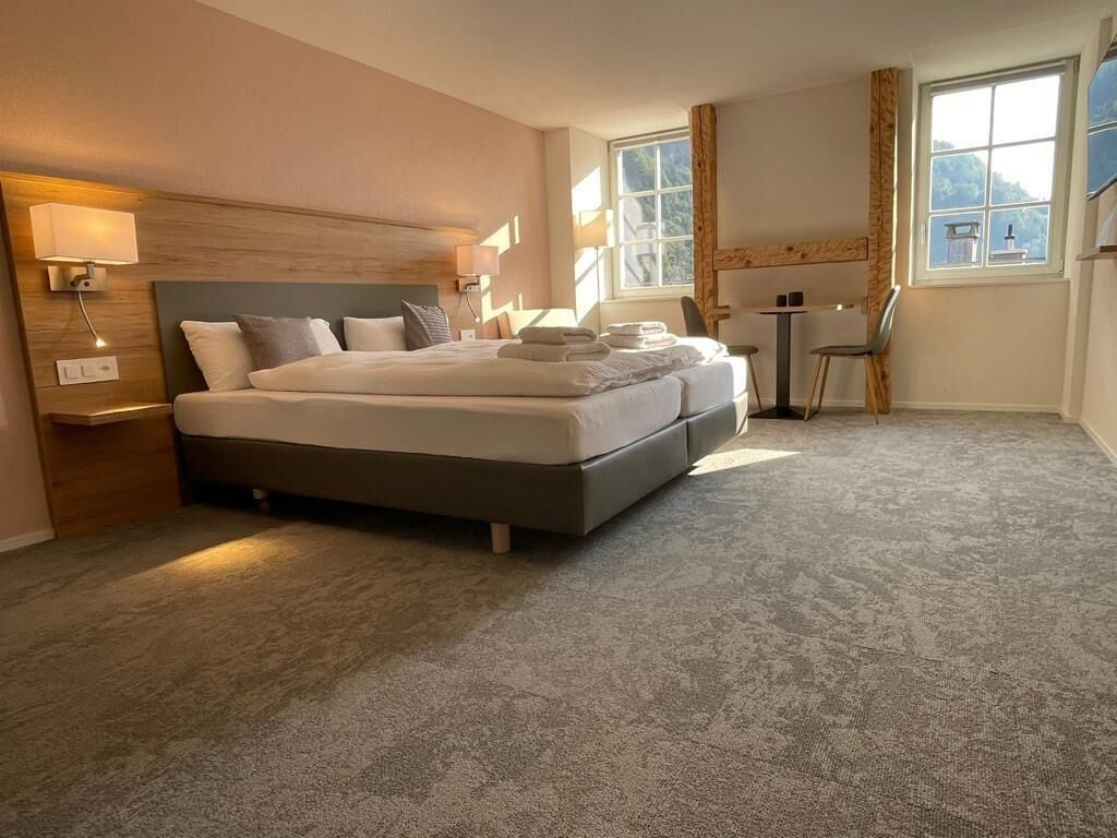 Ett hotellrum med en stor säng, sängbord, ett skrivbord och en stol.