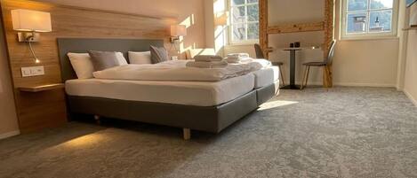 A hotel room with a large bed, bedside tables, a desk, and a chair.