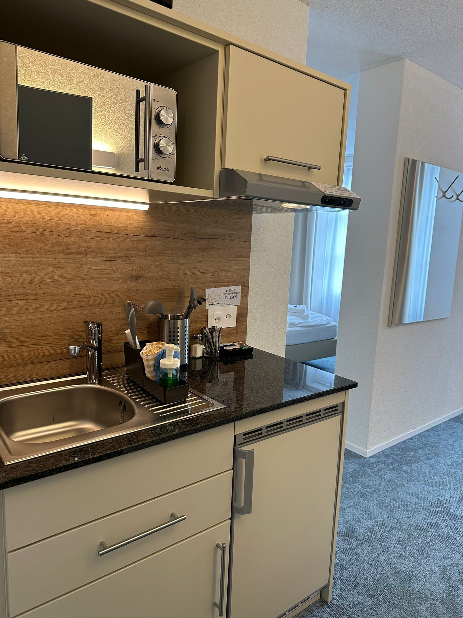 Una cocina moderna con un lavamanos de acero inoxidable, encimera de madera y armarios color beige.