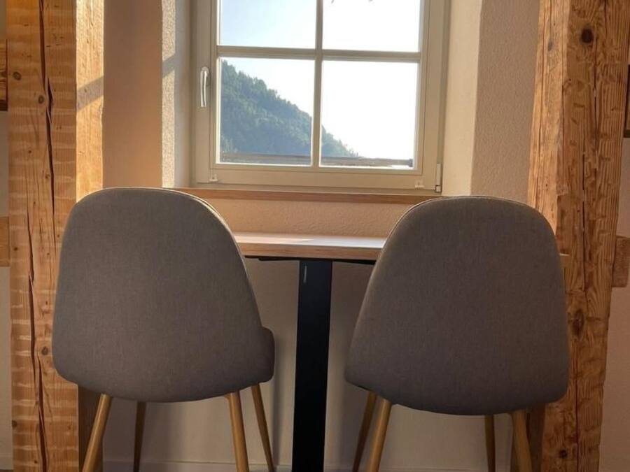 Une pièce avec un bureau et deux chaises, une fenêtre donnant sur une montagne et des murs en bois.