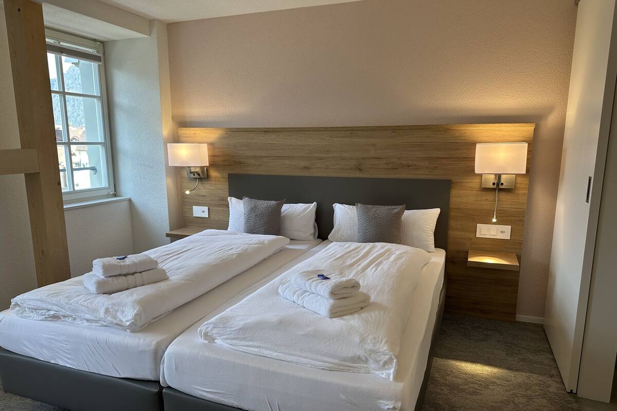 A double bed with two pillows and a bedside table with a lamp.
