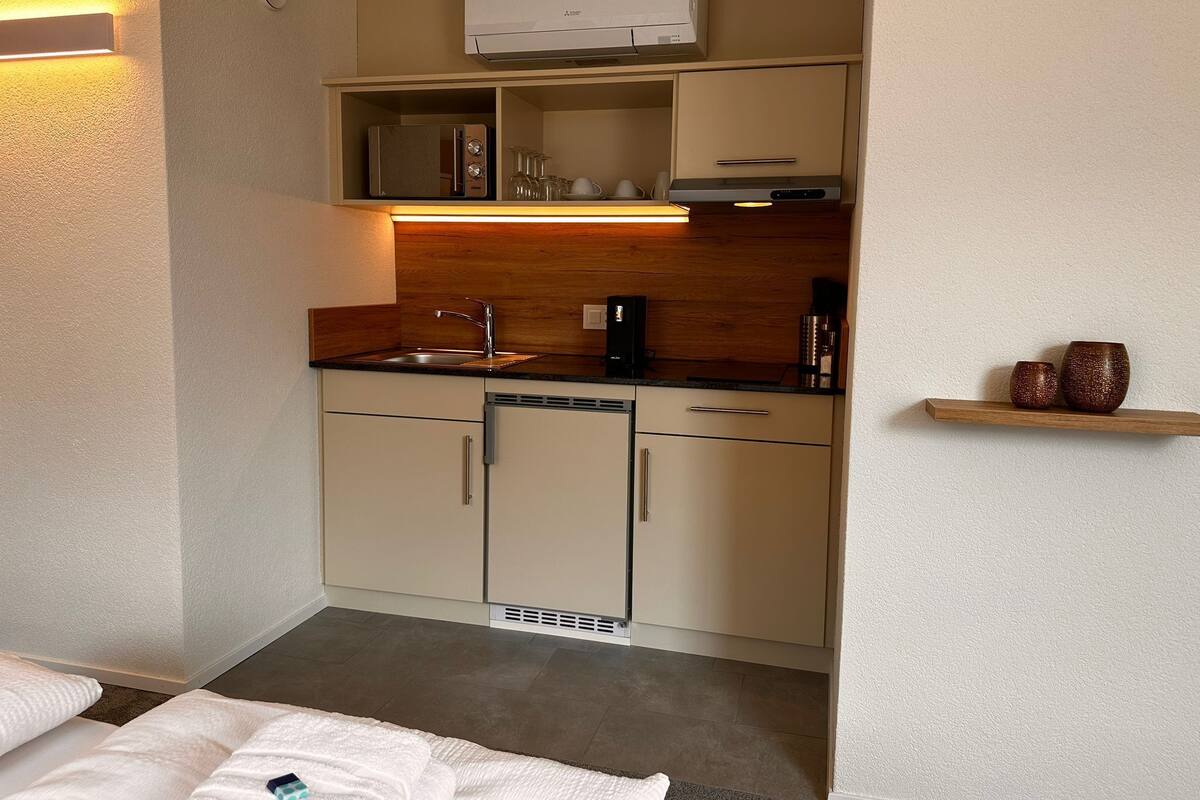 A compact kitchenette with a built-in microwave, a coffee maker, and a small shelf with decorative items.