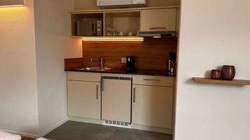 A compact kitchenette with a built-in microwave, a coffee maker, and a small shelf with decorative items.