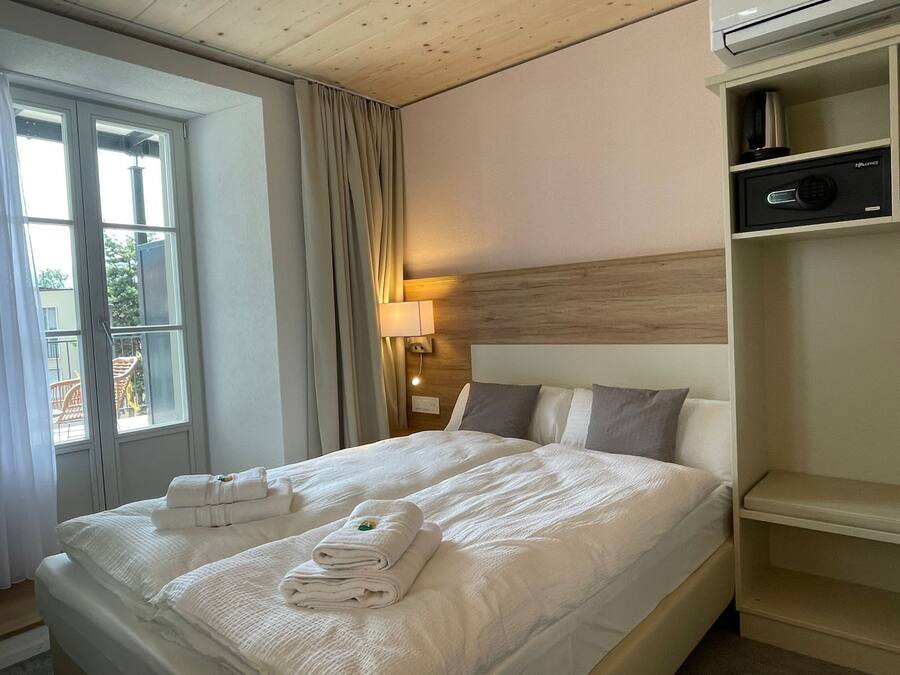 Ett hotellrum med en säng, ett sängbord, en lampa och en hylla med en radio.