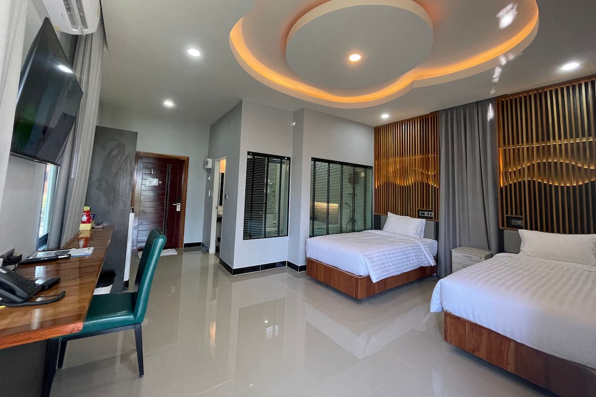 A hotel room with a bed, a desk, a chair, and a TV.
