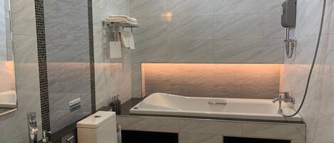 Uma casa de banho moderna com banheira, sanita e lavatório.
