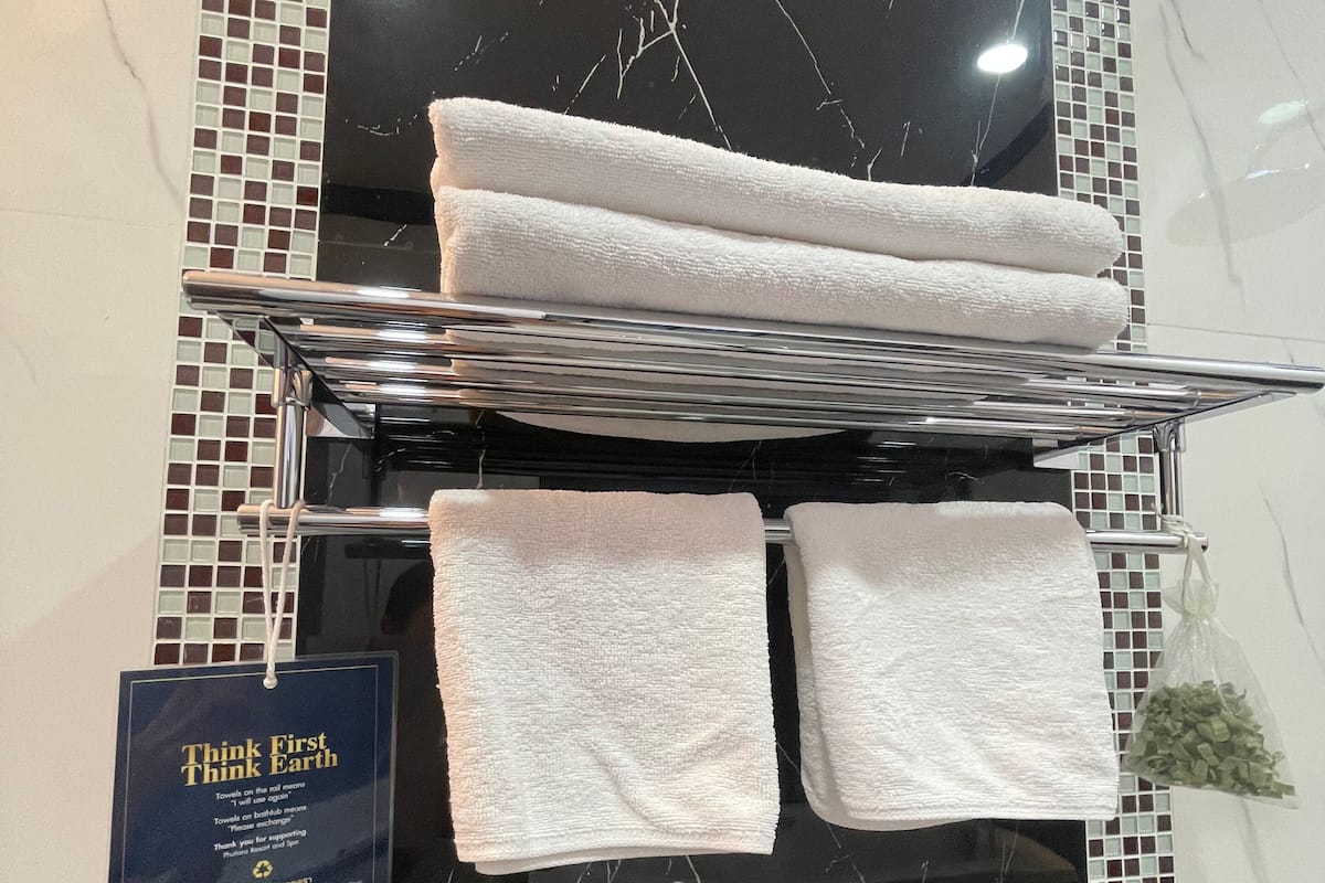 A towel rack with folded towels and a sign about towel usage.