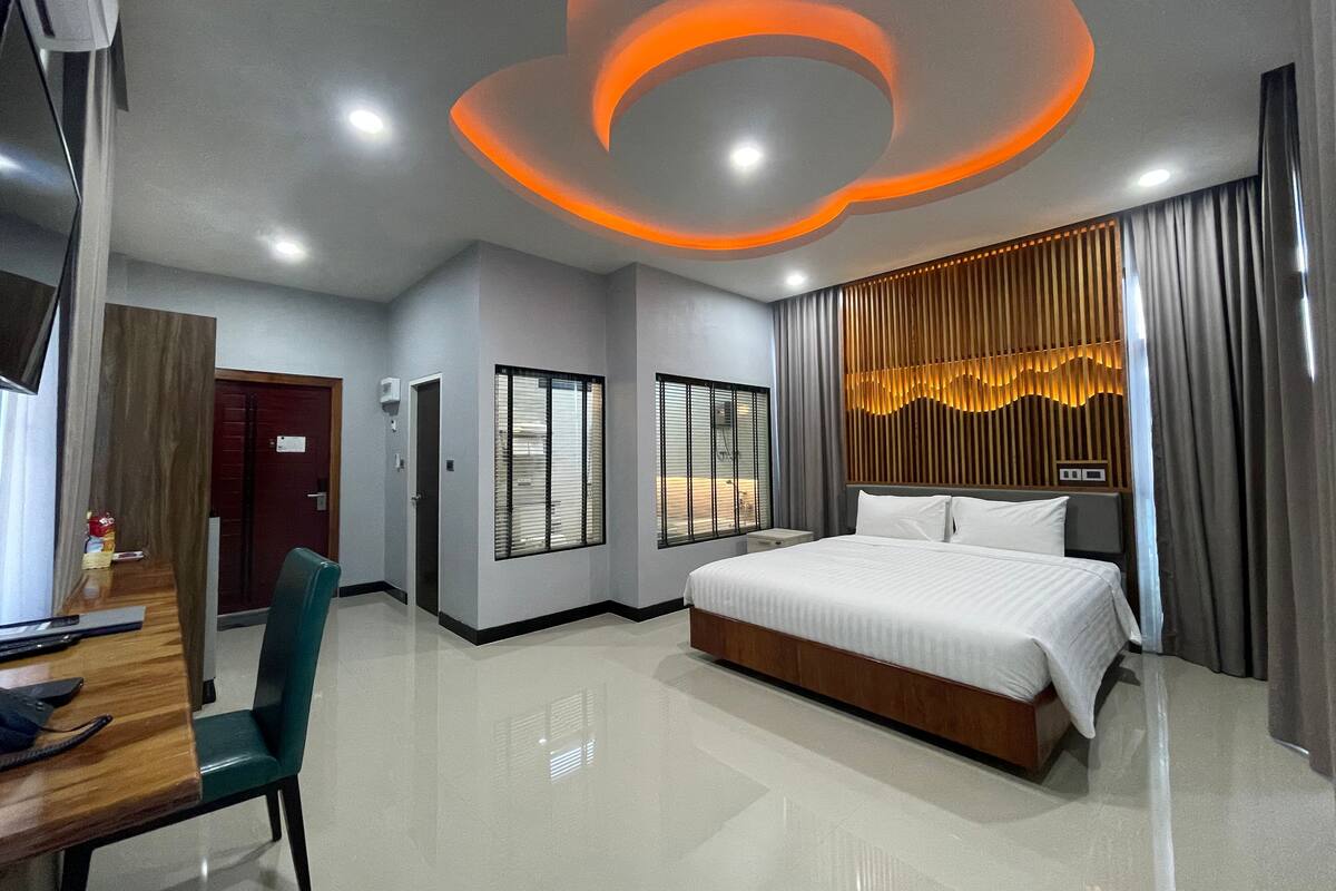 A modern hotel room with a large bed, a desk, and a chair.