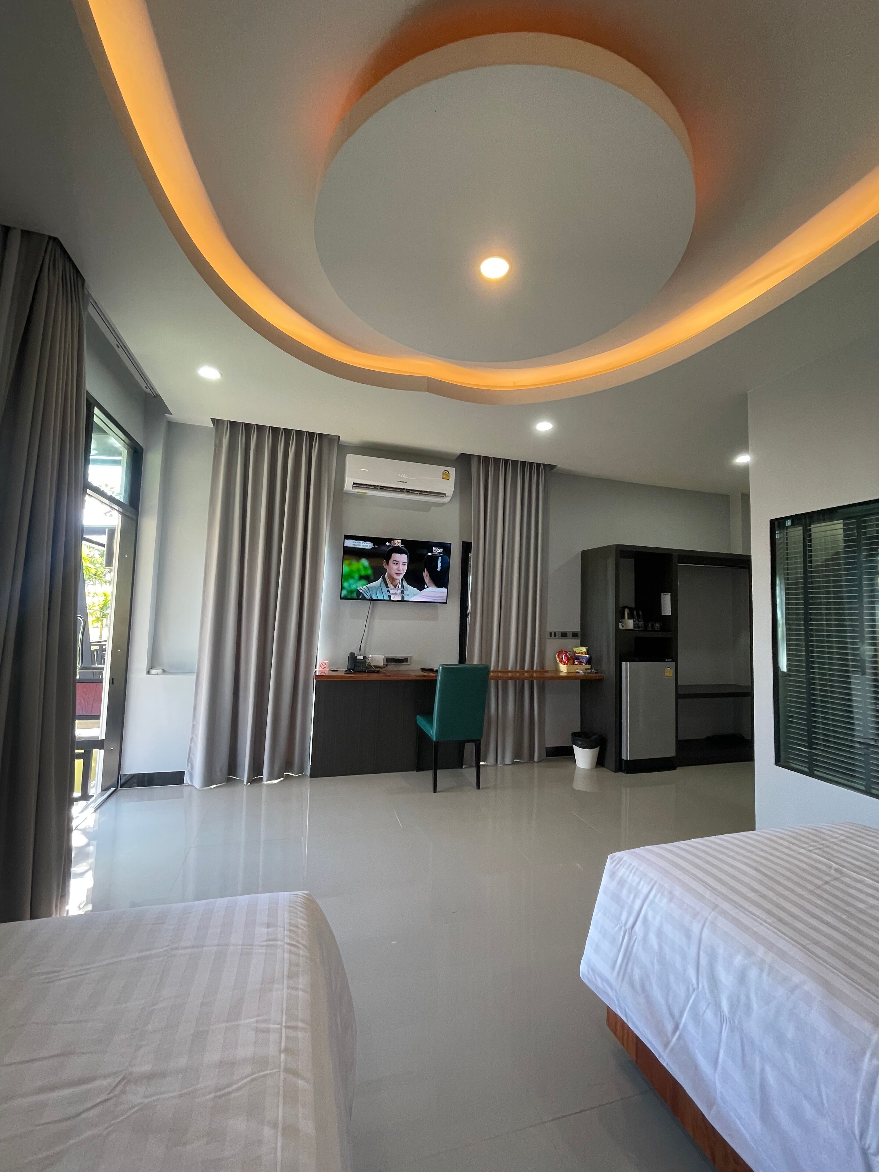 A hotel room with a bed, a desk with a chair, a television, and a kitchenette.
