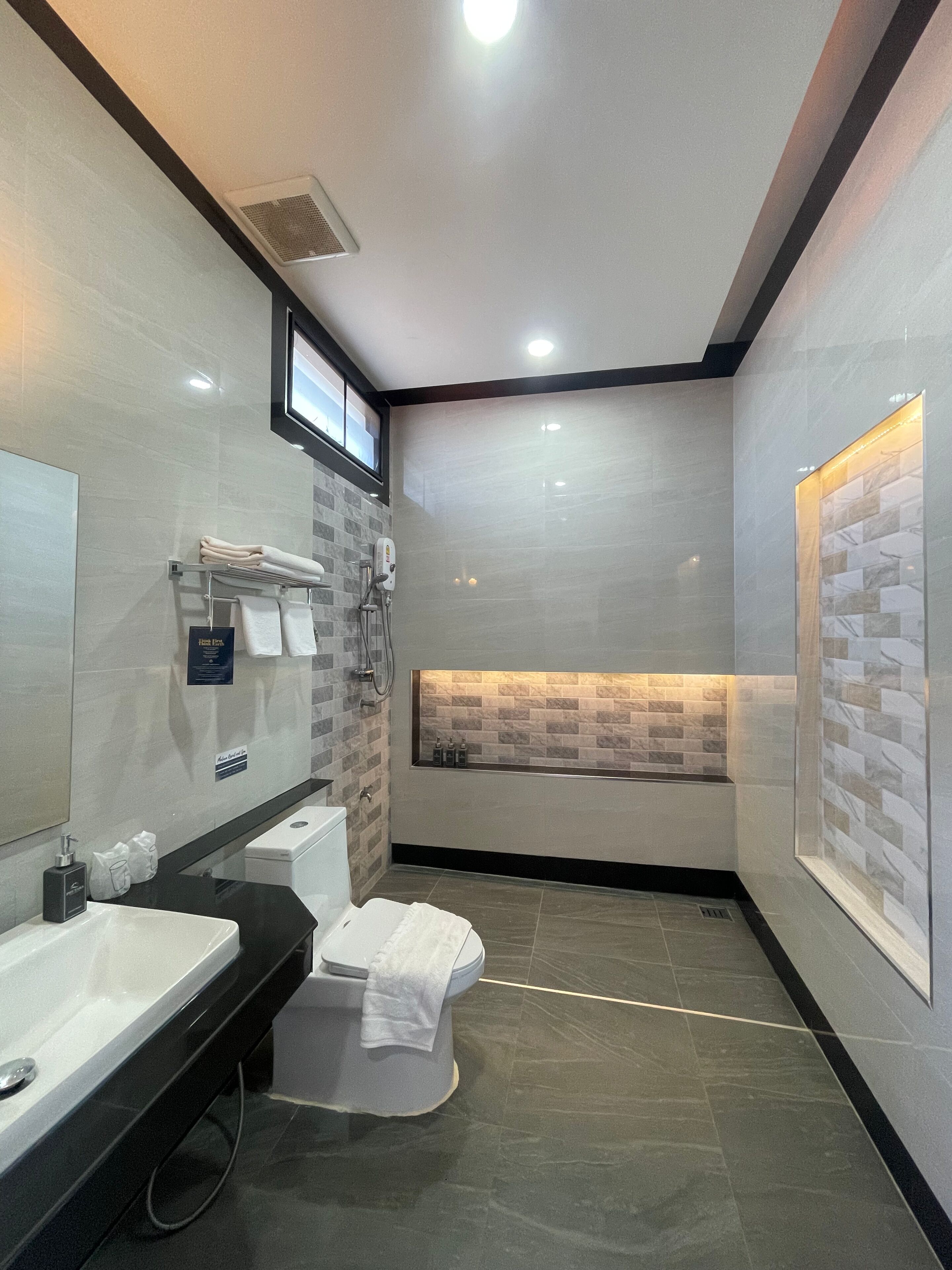 Une salle de bain moderne avec un grand miroir, un lavabo, des toilettes et un espace douche.